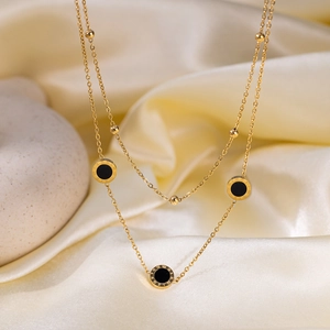 Gold double-layered necklace with black Roman numeral charms on cream silk fabric