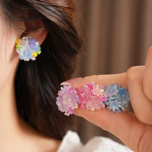 Detailed close-up of colorful resin flower beaded ear clips with intricate floral patterns.