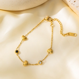 Elegant gold heart bracelet with black stone and zircon on champagne silk background