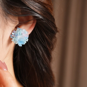Macro detail view of light blue beaded resin flower ear clips for non-pierced ears