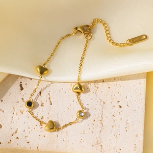Elegant gold stainless steel heart charm bracelet with crystal accents on silk fabric