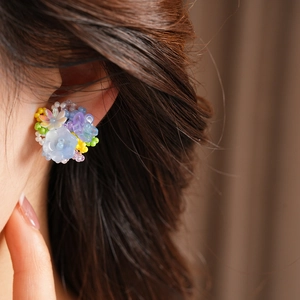 Close-up detail view of colorful resin flower beaded clip-on earrings worn on a female ear