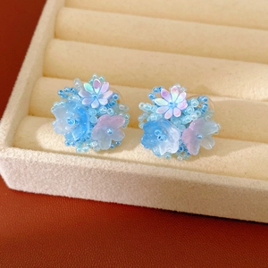 Sweet blue resin floral beaded clip-on earrings displayed in a beige jewelry tray