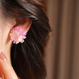 Close-up detail of elegant pink resin flower beaded clip-on earrings on female ear