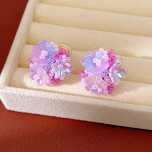 Detail of colorful resin flower beaded ear clips in a beige velvet jewelry tray.