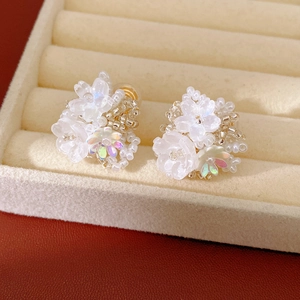 Close-up of white resin flower beaded ear clips with iridescent beads detail