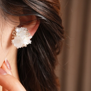 Detailed macro shot of elegant white floral resin beaded ear clip worn on a model's ear