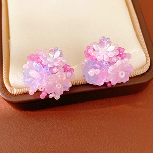 Close-up of sweet purple resin flower beaded clip-on earrings on a display box