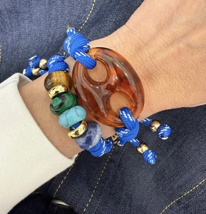 Close-up of handmade braided bracelet with natural stones and pig nose link