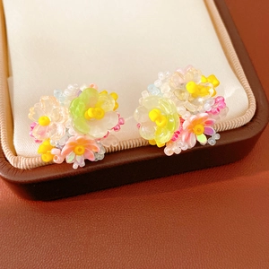 Detailed macro view of colorful resin flower beaded clip-on earrings in a jewelry box
