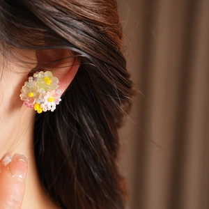 Close-up detail of a colorful resin floral beaded ear clip worn on the model's ear