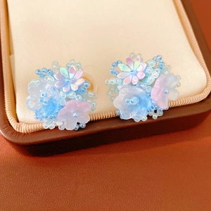 Detailed view of colorful resin flower beaded clip-on earrings in a jewelry box