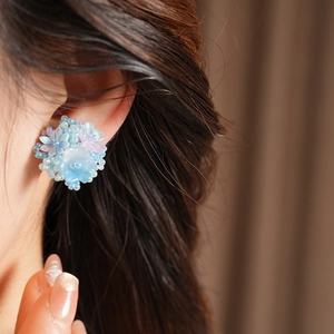 Detail showing blue resin flower beaded ear clip accessory on model for a sweet look