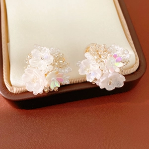 Close-up detail of elegant white resin flower beaded ear clips on a jewelry box cushion