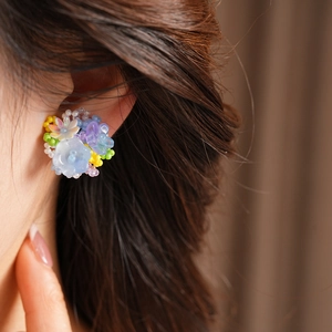 Close-up of colorful resin flower beaded clip-on earrings shown on a person's ear