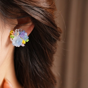 Close-up detail of vibrant colorful resin beaded flower clip-on earrings worn on model's ear.
