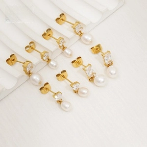 Detalle de cuatro pares de pendientes dorados en forma de C con perlas y circonitas