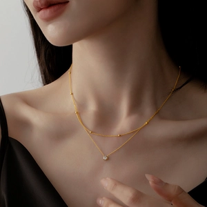Double-layered gold titanium necklace with delicate beads and a single zircon pendant