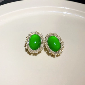 Macro shot of vintage emerald earrings with crystal halo on ceramic display tray