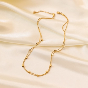 Double-layered gold snake chain necklace with small square cubes on white silk background