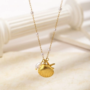 Dettaglio della collana con conchiglia dorata, stella marina e perla barocca bianca