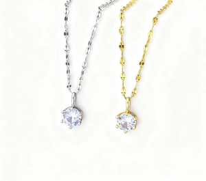Close-up of 18k gold and silver necklaces with six-prong set cubic zirconia and leaf chain