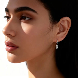 Minimalist silver hoop earrings with round metal charms worn by model to show style