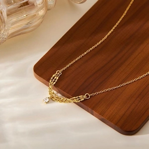 Elegante collana in titanio dorato con catena a spiga e ciondolo in zircone lucido