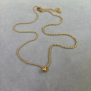 Collier en acier titane doré avec chaînes de perles asymétriques et pendentif boule poli