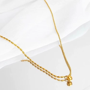 Collier élégant en titane doré avec pendentif boule sur fond de tissu drapé