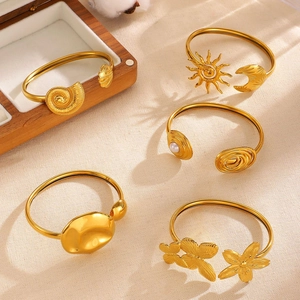 Detailed view of assorted gold stainless steel bangles with sun, moon, and shell motifs