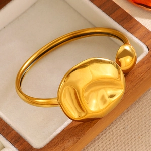 Close-up of a gold asymmetric stainless steel bracelet with organic melted metal design
