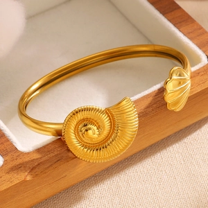 Detailed view of a gold stainless steel asymmetric bangle with seashell and conch design.