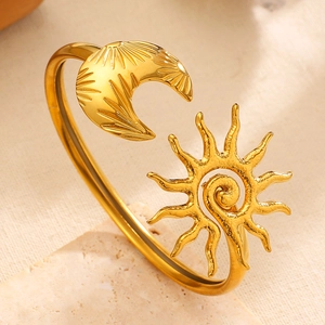 Close-up of gold stainless steel asymmetric cuff bracelet with sun and moon motifs.
