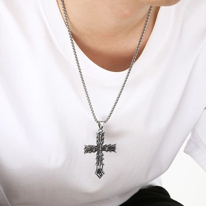 Collar con colgante de cruz gótica de acero inoxidable ennegrecido para hombre en modelo.