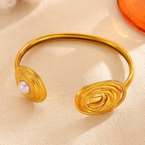 Macro detail view of a vintage gold stainless steel asymmetrical bangle with pearl