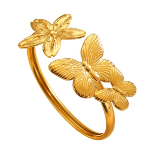 Detailed view of asymmetric gold bangle with butterfly and cherry blossom motifs.