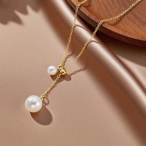 Elegant French gold titanium steel Y-necklace with sliding pearls on velvet background
