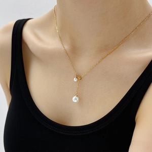 French style Y-shaped gold necklace with double pearls on a model wearing black