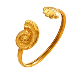 Macro view of gold asymmetric cuff bracelet featuring exquisite seashell and conch ornaments