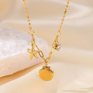 Dettaglio della collana dorata in titanio con ciondoli a stella marina e conchiglia