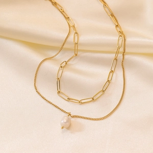 Collana a strati dorata con catena a graffetta e ciondolo di perla su fondo di raso