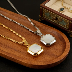 Colliers octogonaux or et argent avec nacre blanche sur un plateau de bijoux