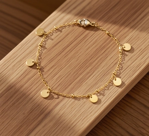 Detailed view of gold round sequin titanium steel anklet on a textured wooden background