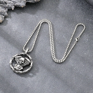 Detailed view of a vintage silver skull and engine pendant on a stainless steel chain.