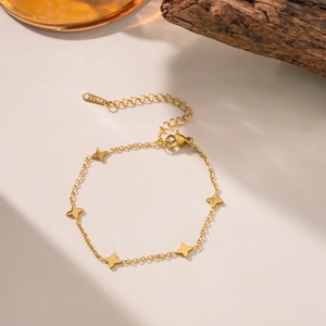 Détail d'un bracelet doré en acier inoxydable orné de breloques en forme d'étoile
