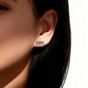 Close-up of three blue opal stones and star pendants on a silver earring worn by a model