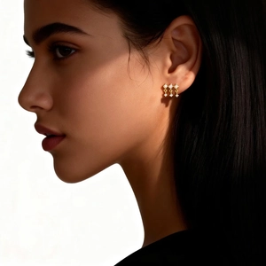 Macro detail of triple gold dangle earrings with sparkling zircon stones on model