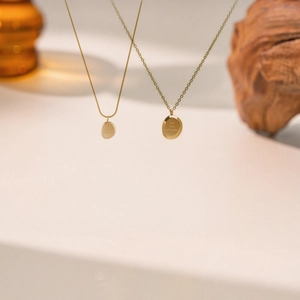 Details von Gold Schlangen und Kreuzketten mit gravierten ovalen Anhängern im Retro Stil