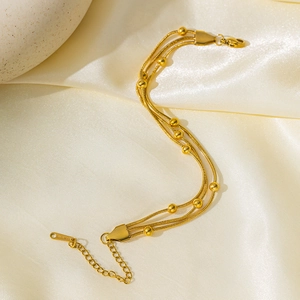Bracelet triple rang en acier inoxydable doré avec perles sur fond de satin